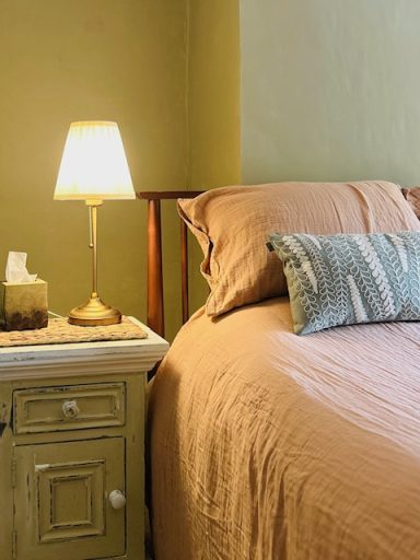 Cozy bedroom with a bed, decorative pillow, and a bedside lamp on a small table.