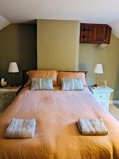 Main bedroom with king size bed, natural cotton muslin bedding, decorative pillows, bedside lights.